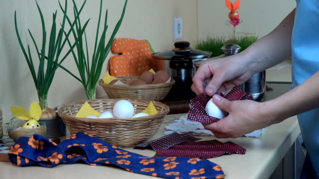 female-hands-put-white-egg-into-silk-material.-Easter-eggs-painting.