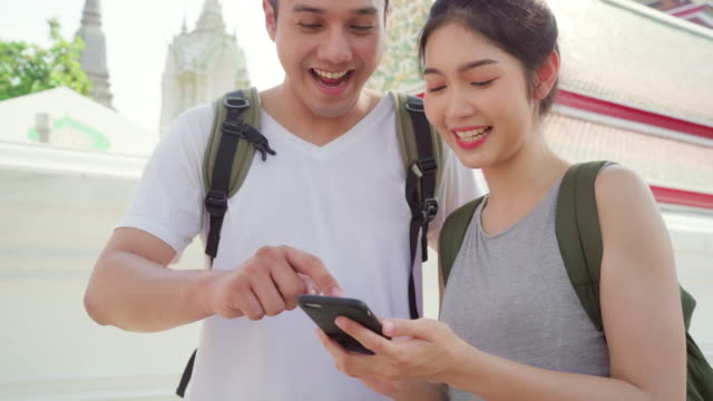 Reisende-asiatische-Ehepaar-Richtung-auf-der-Lagekarte-in-Bangkok,-Thailand,-Ehepaar-mit-Handy-auf-der-Karte-suchen-auf-der-Karte-finden-Wahrzeichen-während-der-Urlaubsreise.-Lifestyle-Paar-Reisen-in-Stadtkonzept.