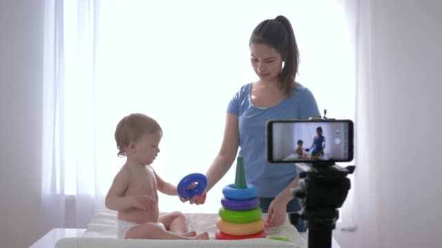 Blogger-Familie,-liebenswerte-Kleinkindjunge-mit-Frauen-Blogger-von-pädagogischem-Spielzeug-gespielt-und-entlastet-sich-beim-Streaming-live-auf-dem-Smartphone-für-Abonnenten-in-sozialen-Netzwerken