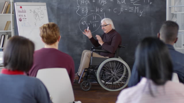 Mature-Disabled-Professor-Writing-on-Chalkboard