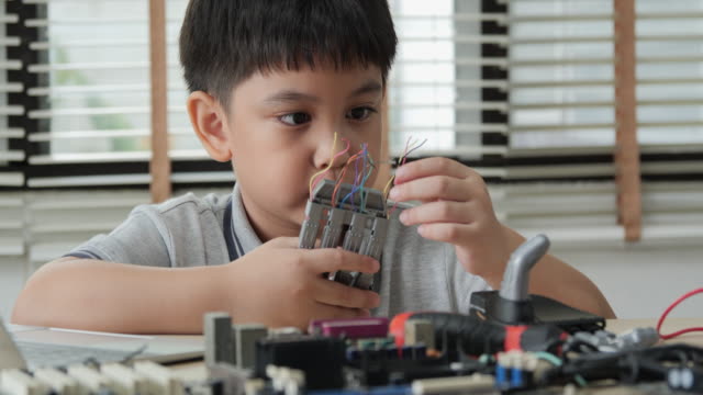 Boy-try-to-fixing-computer-board-in-school-science-club.-Project-for-engineering-club-in-school.-People-with-technology-concept.