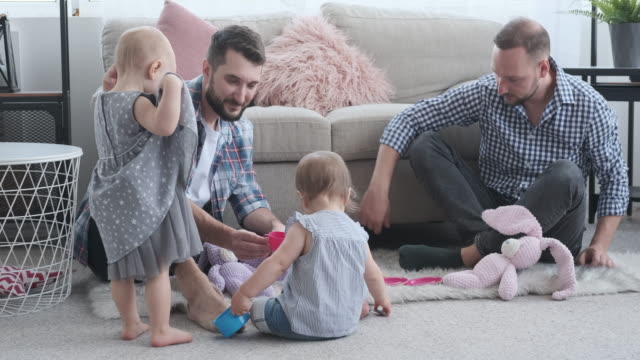 Two-fathers-playing-with-baby-daughters-at-home