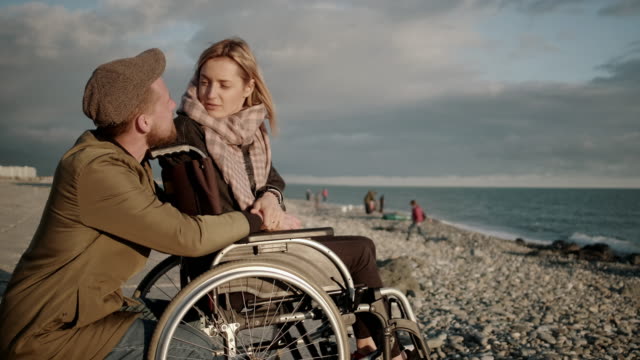 Female-wheelchair-user-and-her-boyfriend-are-chatting-and-viewing-seascape
