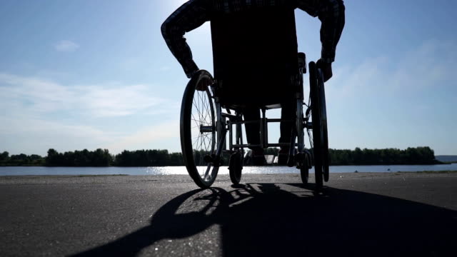 Un-hombre-en-silla-de-ruedas-camina-en-el-paseo-marítimo