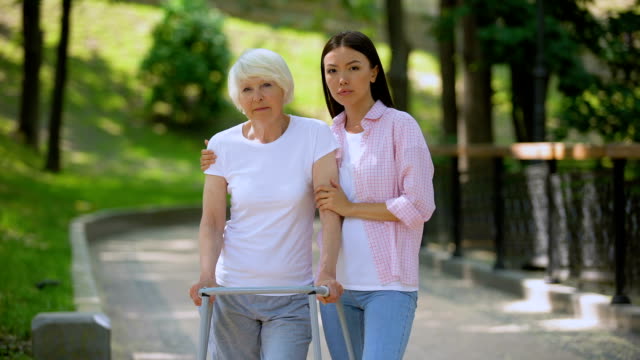 Sad-aged-patient-walking-frame-and-daughter-looking-camera,-social-insecurity