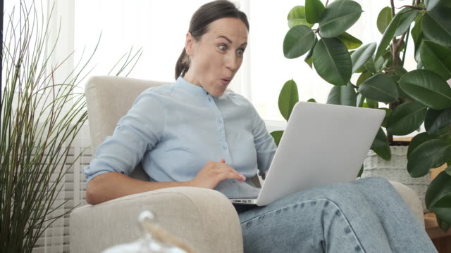 Surprised-woman-receiving-good-news-on-laptop