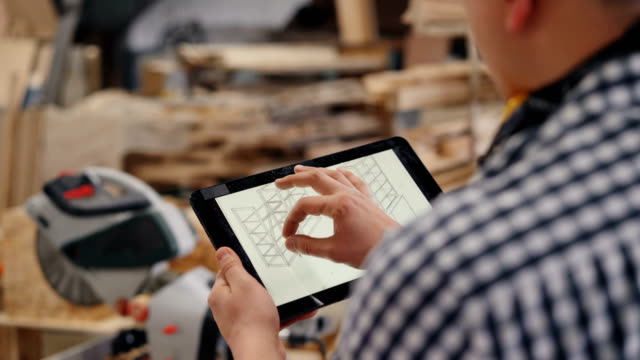 Nahaufnahme-des-Arbeiters-berühren-Tablet-Bildschirm-mit-Design-von-handgefertigten-Möbeln