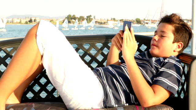 Young-boy-with-smartphone-at-summer-time