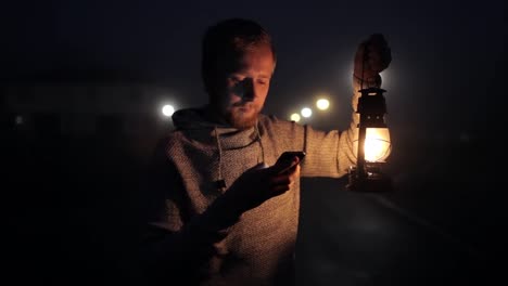 man-with-phone-and-kerosene-lantern-on-a-foggy-street