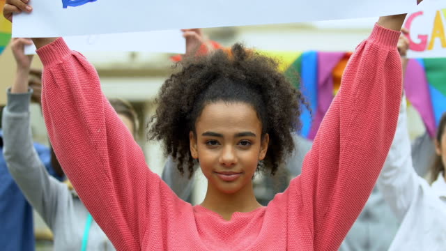 Biracial-Mädchen-hält-Liebe-ohne-Grenzen-Plakat-zusammen-mit-LGBT-Aktivisten