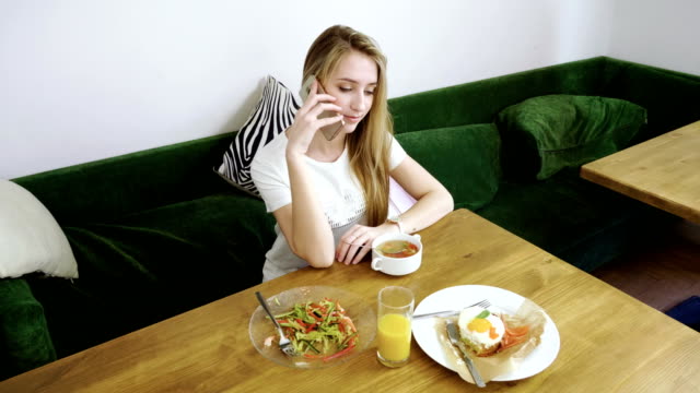 Beautiful-woman-using-mobile-phone-in-modern-cafe-and-talking-on-cell-phone.-4K