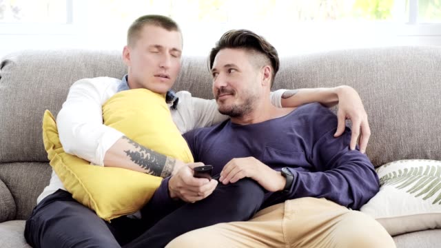 Gay-couple-relaxing-on-couch.-Enjoy-watching-tv,-scare-mood.
