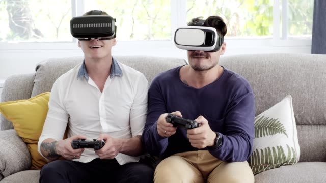 Gay-couple-relaxing-on-couch-playing-virtual-reality-games.-Exciting-mood.-Interesting-mood.