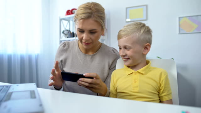 Glückliche-Mutter-und-Sohn-spielen-Spiele-auf-dem-Smartphone-zusammen,-Spaß,-App