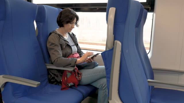 mujer-está-sentada-en-un-tren-sosteniendo-un-teléfono-celular-en-sus-manos-Haciendo-clic-vista-lateral