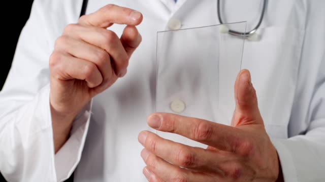 Abgeschnittene-Ansicht-des-Arztes,-der-auf-transparentem-Tablet-Bildschirm-gleitet