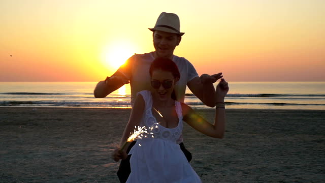Paare-tanzen-mit-einem-Feuerwerk-Kerze-am-Strand-bei-Sonnenaufgang