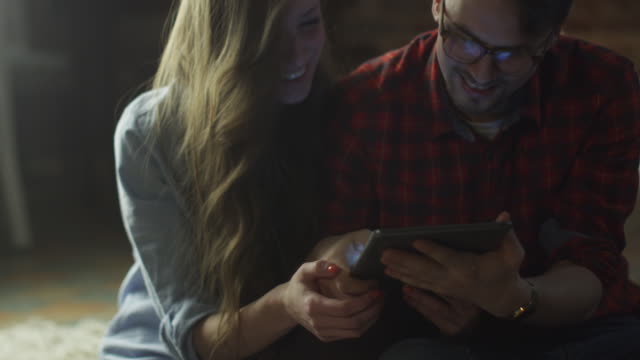 Feliz-sonriente-pareja-de-jóvenes-están-usando-la-PC-de-la-tableta-para-el-entretenimiento-en-casa-en-tiempo-de-la-tarde.