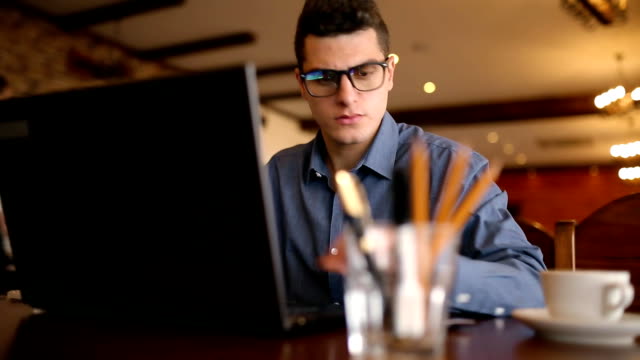 Young-man-shopping-on-the-internet-and-paying-with-credit-card.-Handsome-freelancer-businessman-in-glasses-replenish-his-stock-exchange-account-with-laptop-via-web-application.-Business-concept
