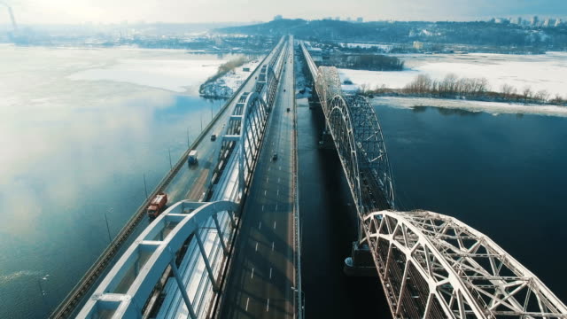 Cars-and-train-moves-on-a-bridge-over-a-frozen-river-aerial-drone-footage