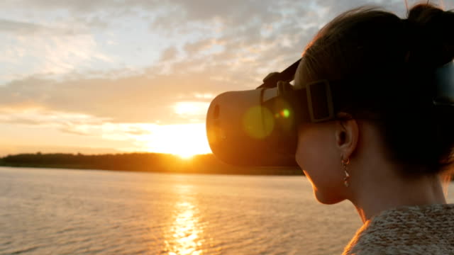 Frau-mit-virtual-Reality-Brille-auf-dem-Deck-des-Kreuzfahrtschiffes-bei-Sonnenuntergang