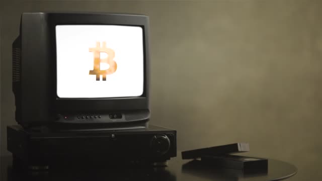 Vintage-TV-auf-Holztisch-mit-Bitcoin.-Alte-TV-zeigt-Bitcoin.-In-der-Nähe-des-Fernsehers-gibt-es-Filmkassetten-und-video-player