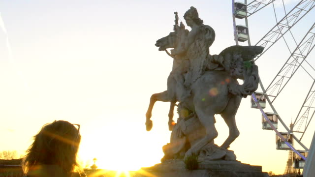 Female-tourist-taking-photo-of-Pegasus-Equestrian-statue-and-Big-Wheel,-sunset