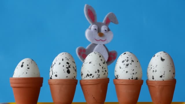 Conejito-de-Pascua-se-esconde-detrás-de-macetas-con-sets-huevos.