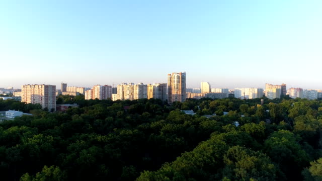 Aerial---City-park,-green-trees-and-tall-buildings.
