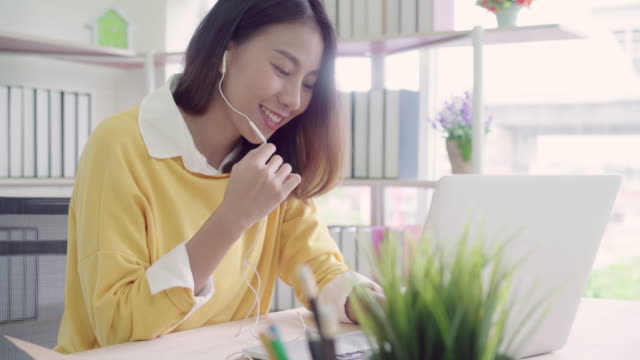 Beautiful-smart-business-Asian-woman-in-smart-casual-wear-working-on-laptop-and-talking-in-a-video-conference-on-line-with-a-headset-with-microphone-in-office.-Lifestyle-women-working-at-home-concept.