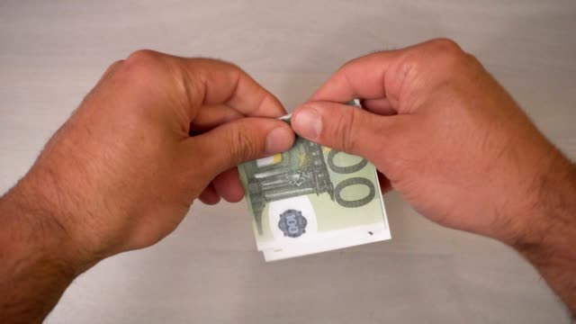 Hands-torn-100-euros