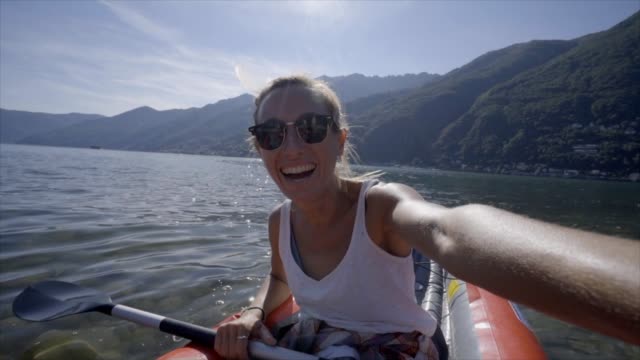 Junge-Frau-unter-Selfie-Porträt-in-rote-Kanu-am-Berg-See-eine-weibliche-genießen-Sommerferien-Spaß-an-Outdoor-Aktivitäten---Zeitlupe