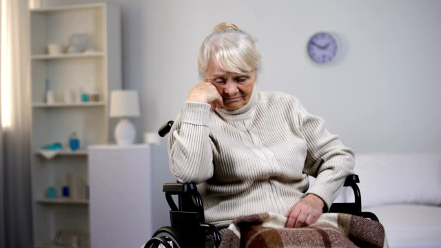 Depressed-old-woman-in-wheelchair-thinking-about-health-problems-at-hospital