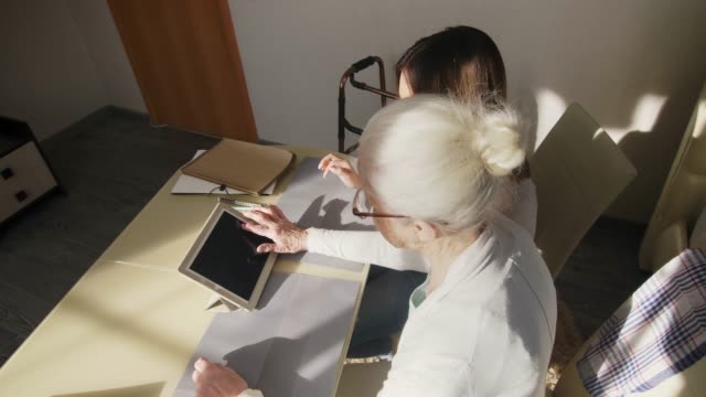 Vista-superior-de-la-mujer-mayor-usando-la-tableta-con-el-voluntario-femenino