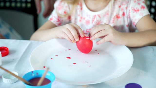 Niña-tratando-de-pelar-huevo-de-Pascua-colorido