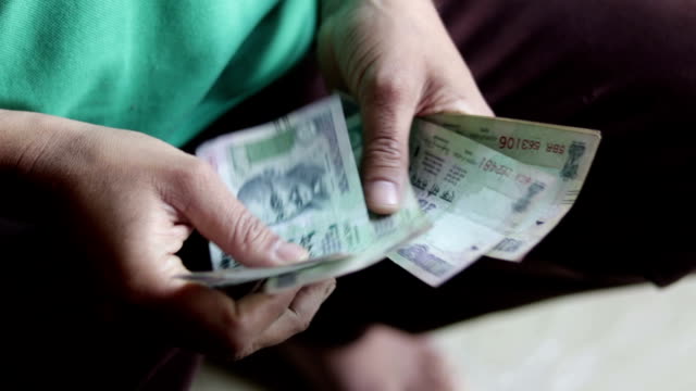 Un-trabajador-contando-billetes-de-moneda-India
