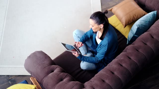 Top-View-lächelnde-Hipster-junge-Frau-entspannt-sich-auf-der-Couch-mit-Tablet-PC