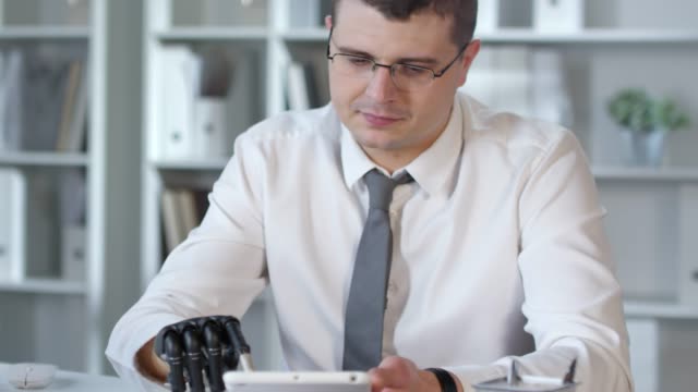Businessman-with-Prosthetic-Arm-Using-Tablet-in-Office