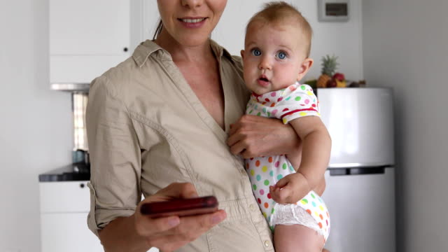 Crop-mother-with-baby-using-smartphone