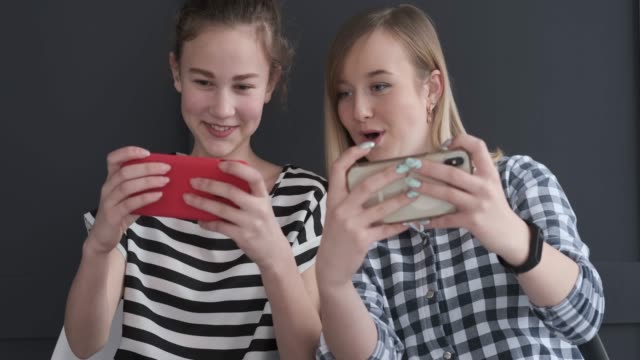 Aufgeregte-Mädchen-im-Teenageralter-spielen-auf-Mobiltelefonen