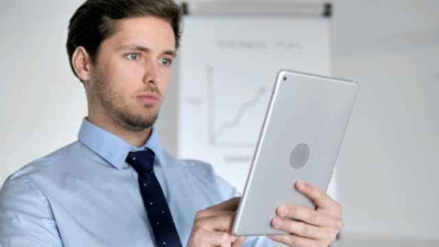 Close-Up-of-Young-Businessman-Using-Tablet-in-Office