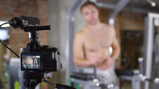 Shirtless-Man-Showing-Leg-Raises-on-Parallel-Bars-on-Camera
