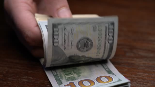 slow-motion-closeup-hand-flips-new-hundred-dollar-bills-money