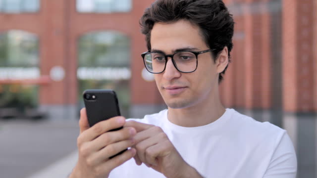 Outdoor-Portrait-of-Young-Man-Using-Smartphone