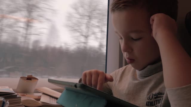 Niño-que-pasa-el-tiempo-con-la-almohadilla-durante-el-viaje-en-tren