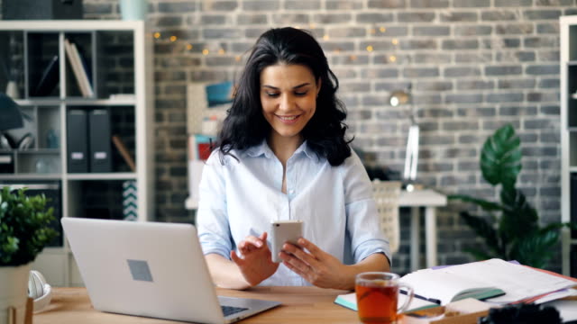 Woman-with-smartphone-enjoying-social-media-at-work-touching-screen-smiling