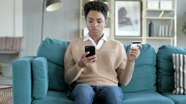 El-joven-africano-usando-tarjeta-de-crédito-en-el-teléfono-celular