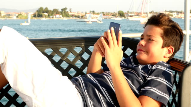 Young-boy-with-smartphone-at-summer-time