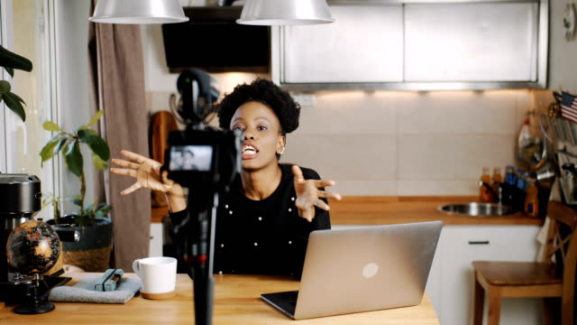 Glückliche-junge-schöne-schwarze-Lifestyle-Bloggerin-machen-neue-Unterhaltung-Video-mit-Kamera-zu-Hause-Zeitlupe.