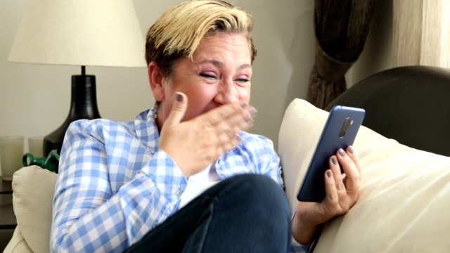 Woman-with-smart-phone-laughing-at-the-home